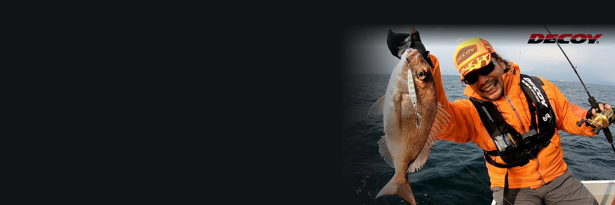 Angler in Decoy cap and vest holding a snapper caught on a jig